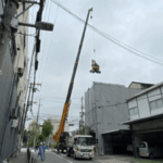 狭小地の鉄骨3階建ての解体工事で、重機楊重と呼ばれる、クレーンで重機を吊り上げて3階の床に置く作業。重機を屋上ではなく3階の床に置く。撤去したALCパネル等の廃材もクレーンで降ろします。
