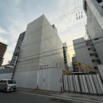 飛散防止のパネルで四方を覆われたビルを斜めに道路から見た写真